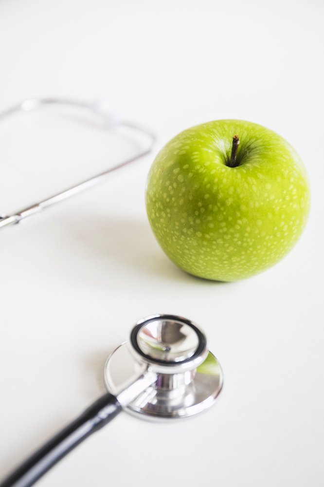 Green apple beside a stethoscope, symbolizing pediatric nutrition care